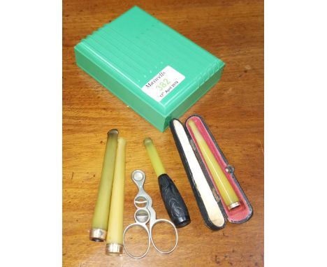 Three gold tipped cigarette holders, cigar scissors and green Bakelite box 