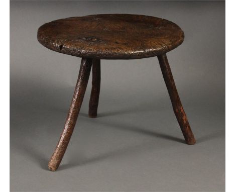 An 18th Century Elm Primitive low OCCASIONAL/CRICKET TABLE with knarled circular top on three splayed stick legs 47cms diam 3