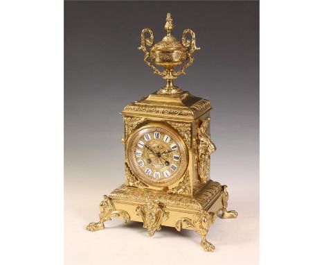 An ornate late 19th Century French Cast Brass MANTEL CLOCK with urn surmount, ringed mask side handles and cast leaf work cla