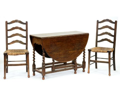 A pair of rush seated stained ash ladder back chairs and an oak gateleg table on spiral legs  Typical but minor wear from use