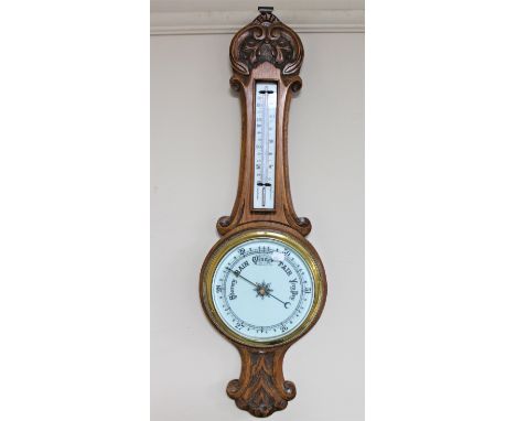 An early 20th century carved oak cased barometer with enamel dial 