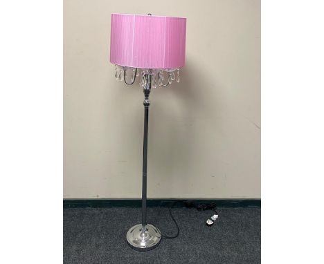 A contemporary metal four branch floor lamp with glass drops and pink shade