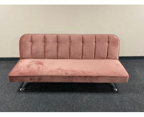 A contemporary folding bed settee in pink fabric on metal legs 