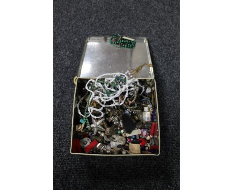 A tin of beaded necklaces, enamel badges, tie pins etc 