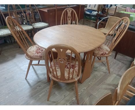 A modern Ercol light elm drop leaf table and four swan back chairs.