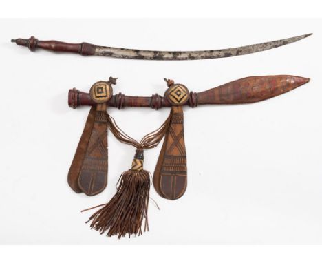 An early 20th century West African Mandigo sword:, the curved blade with single fuller, shaped leather bound handle, in a bro