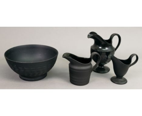 A group of black basalt teawares, 20th century, comprising: an engine turned bowl, 16cm diameter and three milk jugs, largest