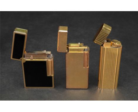 Cartier; a gilt metal lighter of rounded rectangular design with ribbed detailing, number C85847, in a Cartier red fabric pou