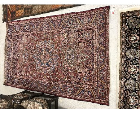 A Persian rug, the central panel set with foliate decorated medallion of stylised flower head form within a floral decorated 
