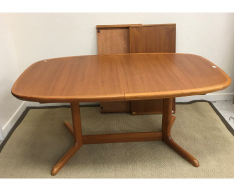 A Danish teak rounded rectangular extending dining table in the manner of Niels Koefoed on end pillar supports united by a ce