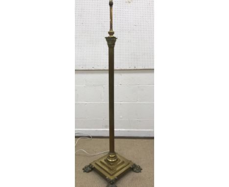 An early 20th Century brass Corinthian column standard lamp on a square stepped plinth base to heavy splayed lion's paw feet 