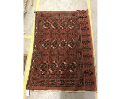 A Tekke Bokhara rug, the central panel set with three repeating rows of stylised elephant foot medallions on a red ground wit