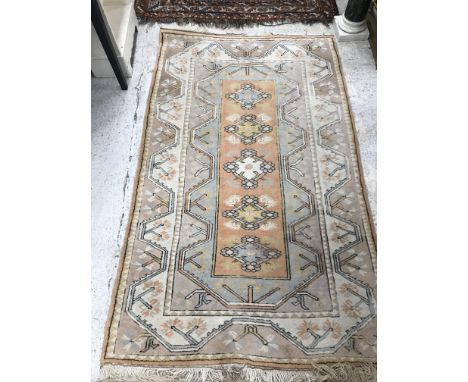 A Caucasian rug, the central panel set with five repeating medallions on a salmon pink ground, within a stepped salmon pink, 