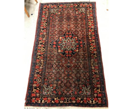 A vintage Persian carpet, the central panel set with floral decorated medallion on a red floral decorated ground, within a st