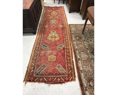 A Turkish runner, the central panel set with stylised foliate motifs on a red ground within a stepped red and orange border a