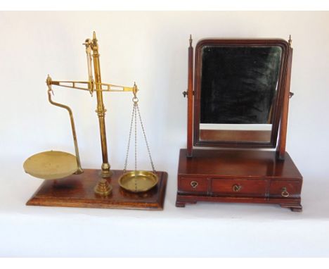 A Georgian mahogany swing mirror upon a base fitted with three cushion drawers together with a further set of brass weighing 