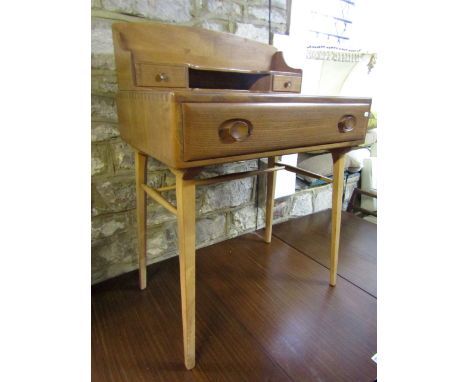 A good Ercol light elm desk, the raised back fitted with two short drawers flanking an open recess over a base fitted with a 