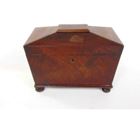 A Regency flame mahogany sarcophagus tea caddy with ring handles and hinged lid enclosing a fitted interior.