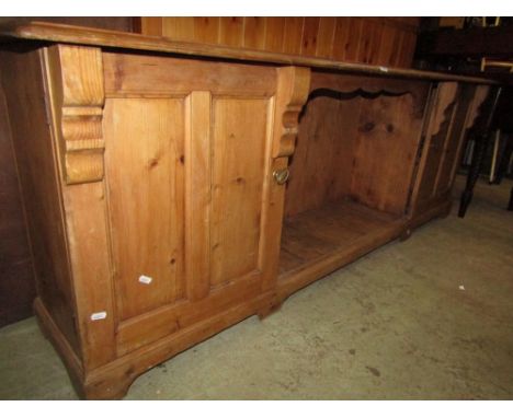 A Victorian stripped and waxed pine side cupboard, the central alcove flanked by two panelled cupboards raised on short brack