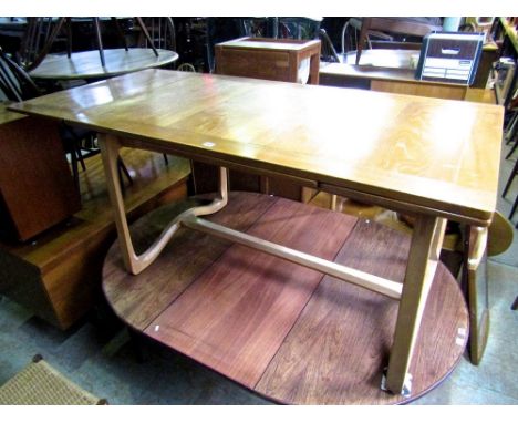 A rare and interesting Ercol light elm extending dining table upon a stylised swept chamfered base united by a stretcher.