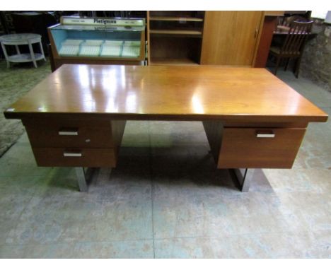 A 1970s teak and chrome twin pedestal desk fitted with an arrangement of five drawers to the kneehole frieze upon good chrome