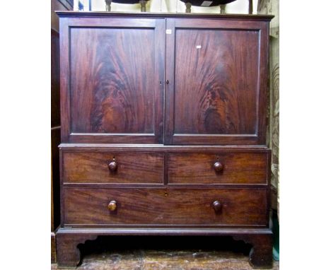 A George III mahogany dwarf linen press, the lower section enclosed by one long and two short drawers, the upper section encl
