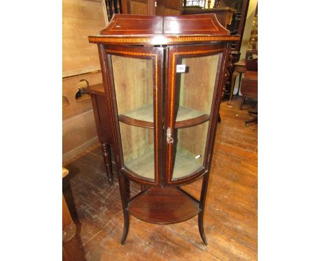 A freestanding inlaid Edwardian mahogany bow fronted corner cupboard, the upper section enclosed by a pair of convex glazed d
