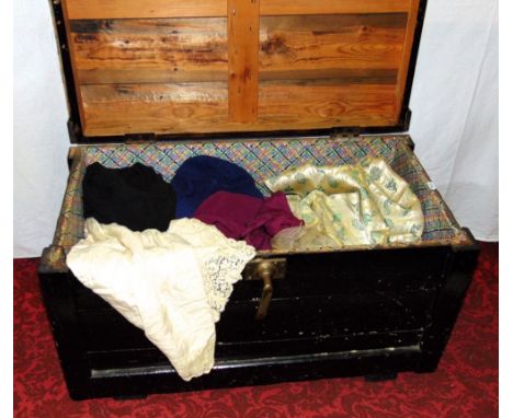 A Wooden trunk with upholstered lid containing a quantity of vintage clothing including a 1950s dance dress and stole, a 1920