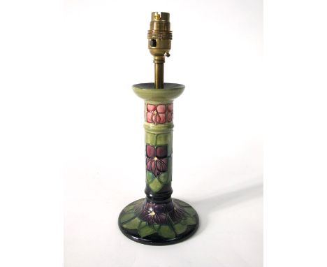 A Moorcroft lamp base with stylised purple violet floral and leaf decoration on a green and black ground with impressed marks