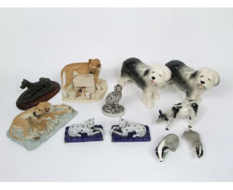 A 19th century Staffordshire model of a seated Dalmatian, together with a pair of reproduction Staffordshire models of recumb