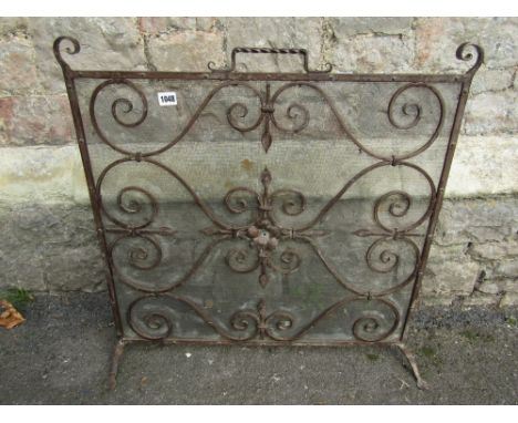 A good quality hand wrought iron work firescreen with scrolled detail and mesh back, 70 cm wide