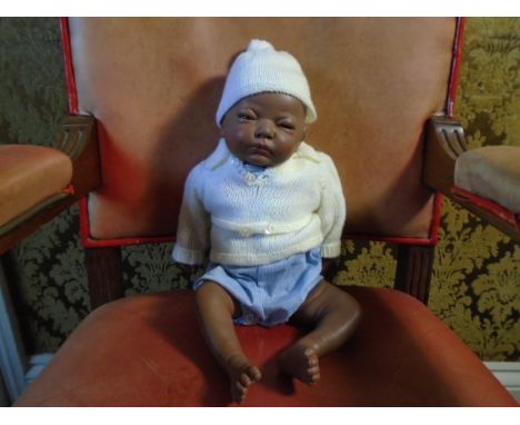 A 17 inch  full porcelain body new born doll,  marked 'Joyee' on inside leg. slightly loose limbs dressed in a blue and white