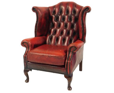 A Georgian style red button leather upholstered wingback chair, on cabriole legs with pad feet.