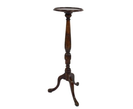 A walnut torchere, the circular dished top on a leaf carved and turned column, on a tripod base, 92cm high.