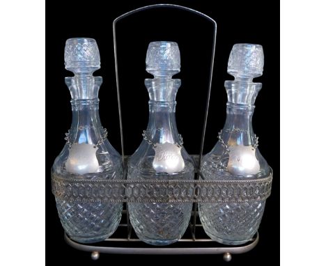 A pierced metal three division Tantalus, containing three moulded glass decanters with labels for whiskey, port and sherry, 2
