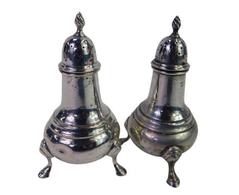 A pair of George V silver pepper pots, each of baluster form with a flamed finial, raised on three hoof feet, Birmingham 1920