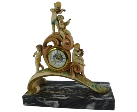 A 20thC Italian resin mantel clock, the circular dial bearing Roman numerals, key wind, the case decorated with putti playing