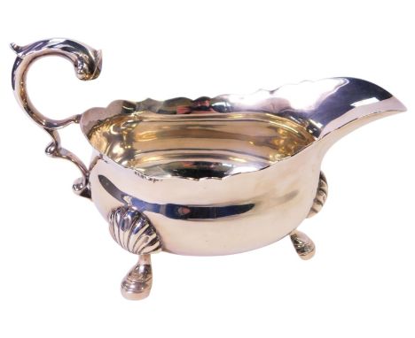 A George V silver sauce boat, with a gadrooned rim, acanthus scroll handle, raised on three shell-capped hoof feet, Edward Ba