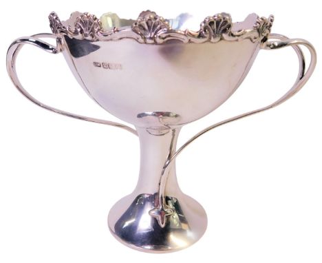 An Edward VII silver twin handled cup, the border decorated with scrolls and shells, with two open twisted handles, on a cyli