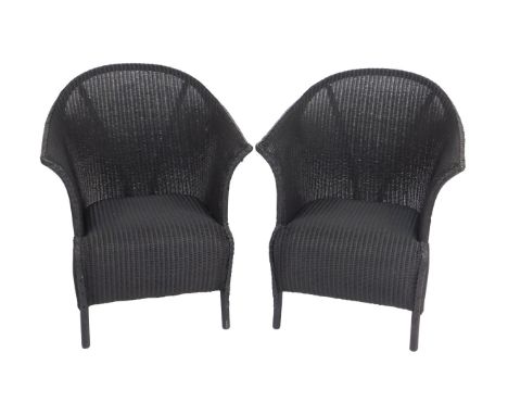 A pair of Lloyd Loom Spalding black painted armchairs, each with cylindrical legs.