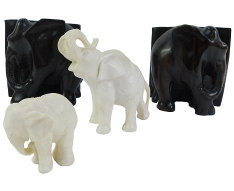 A pair of lignum vitae bookends, modelled as elephants, 20cm high, together with a carved alabaster elephant with trunk raise