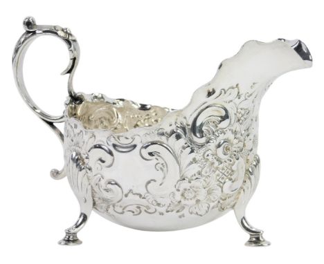 A Victorian silver cream jug, with a waved border, with embossed and bright cut decoration of flowers and scrolls, a scroll h