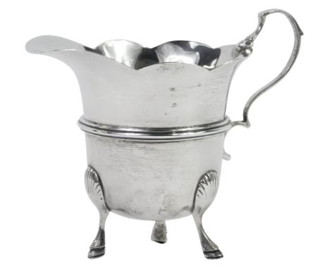 A Victorian silver cream jug, with a waved rim, raised central band, on three shell capped hoof feet, William Atken, Chester 