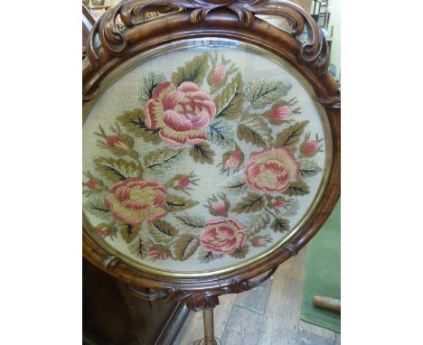A good Victorian carved walnut pole screen on a tripod base on carved column, the circular frame with scroll and floral detai