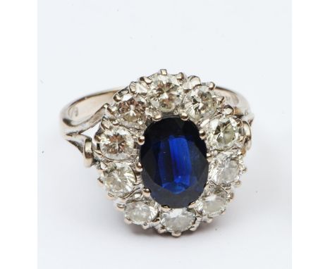 A sapphire and diamond flower head cluster ring, centred with an untested oval mixed-cut sapphire weighing approximately 1.90