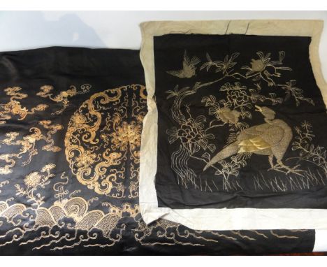 A black ground oriental embroidered panel with gold wirework woven decoration containing a central circular medallion with dr