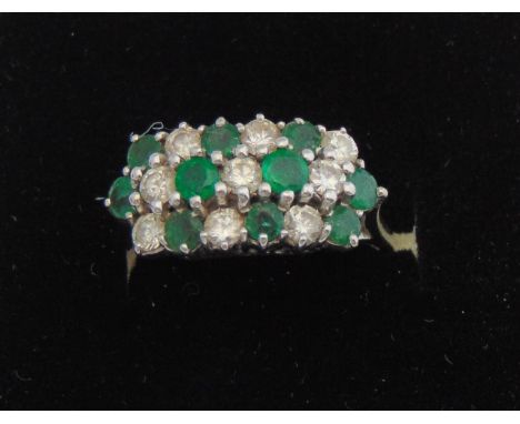 An emerald and diamond cluster ring, set with three rows of alternating round mixed-cut untested emeralds and round brilliant