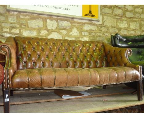 A Georgian style leather sofa with raised back and scrolled arms and with overall buttoned finish, raised on square tapered s
