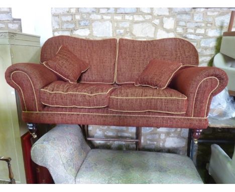 A good quality 2-seat sofa with scrolled arms and shaped back in a brushed burgundy colourway, raised on turned supports