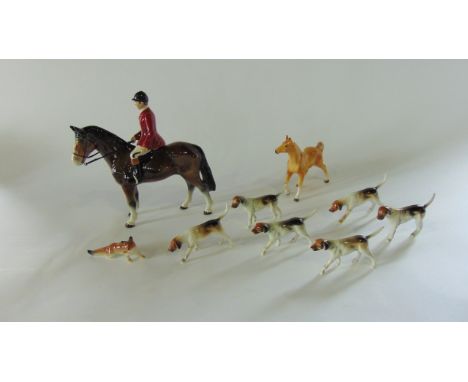 A collection of ceramic hunting related figures in the Beswick manner comprising a huntsman on a brown horse, six hounds and 